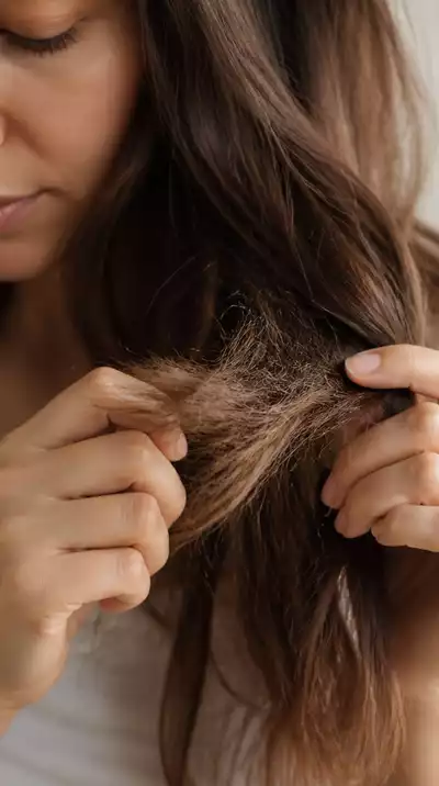 Woman examining her hair for split ends and dryness, close up, natural light