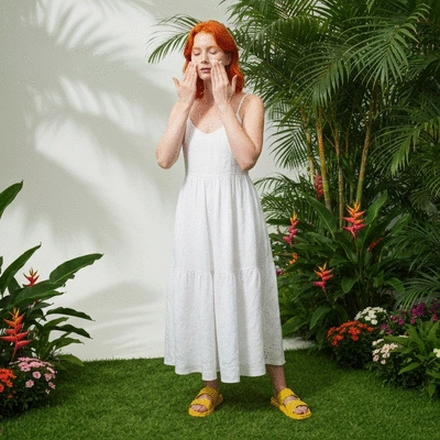 Woman applying lightweight gel moisturizer to her face in a tropical setting